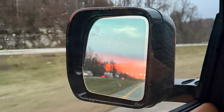 Sunset in the rearview mirror of a car